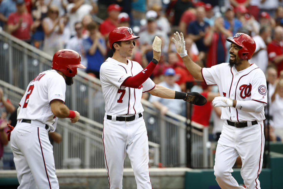 Washington Nationals' Anthony Rendon, right, high-fives teammates Adam Eaton, left, and Trea Turner after batting them in on a home run in the fifth inning of a baseball game against the Colorado Rockies, Thursday, July 25, 2019, in Washington. (AP Photo/Patrick Semansky)