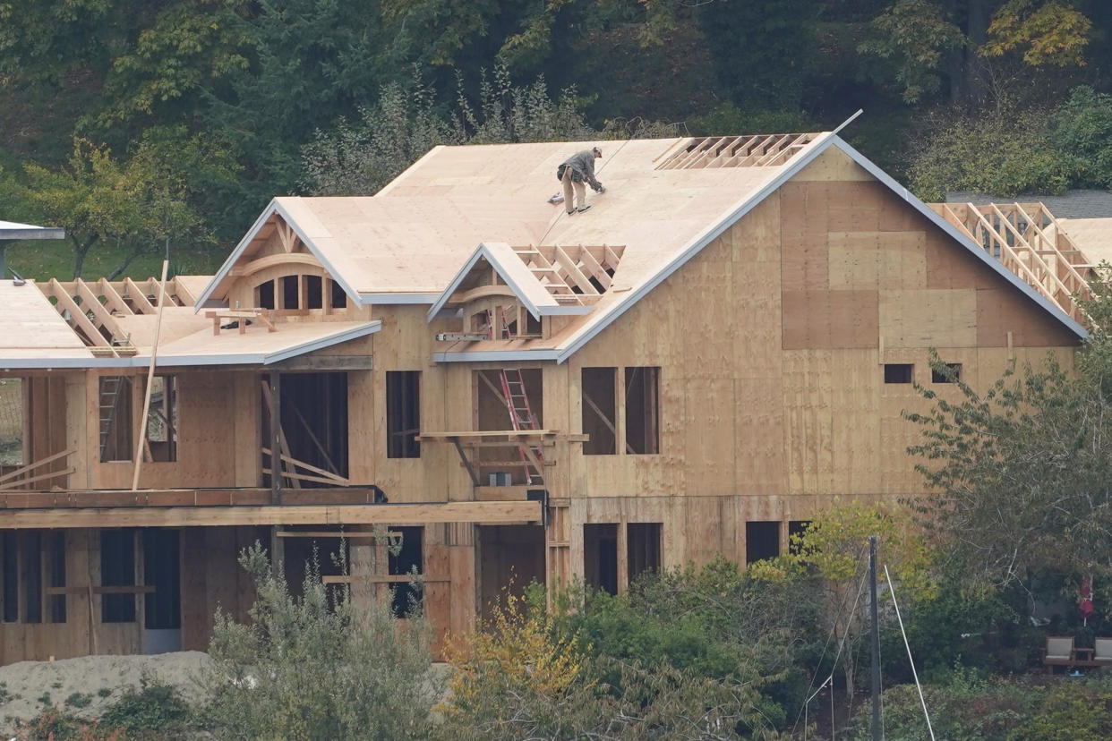 A worker walks on the roof of a home under construction, Wednesday, Oct. 28, 2020, along the waterfront in Gig Harbor, Wash. (AP Photo/Ted S. Warren)