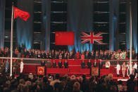 FILE - In this July 1, 1997, file photo, world dignitaries and other guests to the Hong Kong handover ceremony stand and watch the Chinese flag, left, flying after the Union Jack was lowered at the Hong Kong Convention Center. Hong Kong has been living on borrowed time ever since the British made it a colony nearly 180 years ago, and all the more so after Beijing took control in 1997, granting it autonomous status. A national security law approved by China's legislature on May 28, 2020 is a reminder that the city's special status is in the hands of Communist Party leaders who have spent decades building their own trade and financial centers to take Hong Kong's place. (Kimimasa Mayama/Pool Photo via AP)