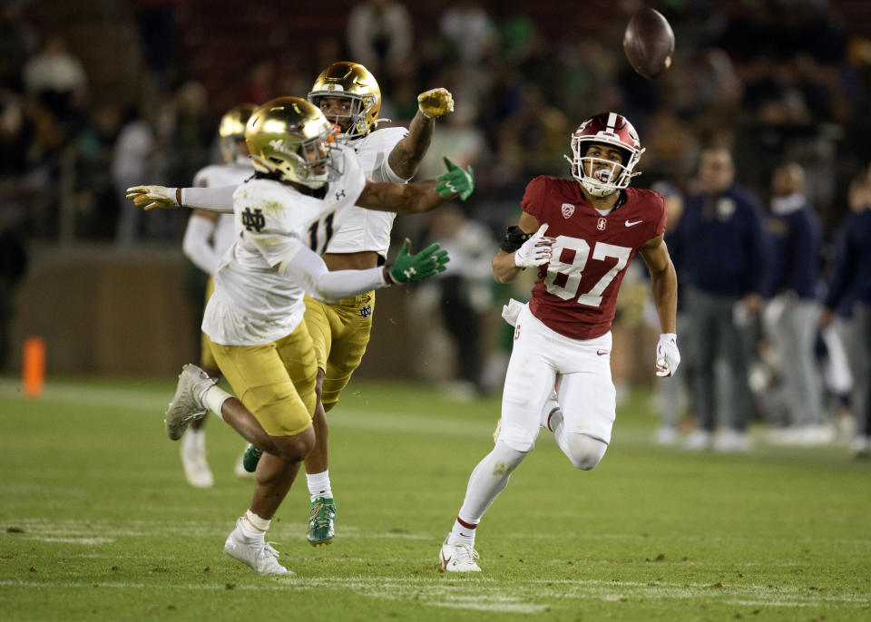 Nov 25, 2023; Stanford, California, USA; Neither Notre Dame Fighting Irish safety Ramon Henderson (left), cornerback Clarence Lewis (6) nor Stanford Cardinal wide receiver Jason Thompson (87) can get to a deep pass during the fourth quarter at Stanford Stadium. Mandatory Credit: D. Ross Cameron-USA TODAY Sports