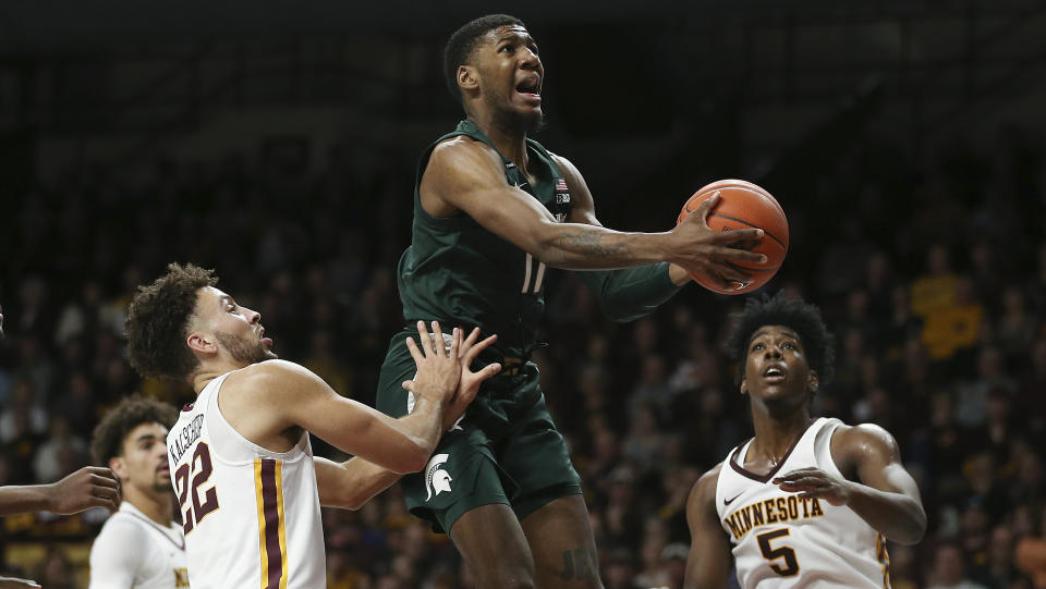 Michigan State's Aaron Henry, center, pushes up toward the basket against Minnesota's Gabe Kalscheur during an NCAA college basketball game Sunday, Jan. 26, 2020, in Minneapolis. (AP Photo/Stacy Bengs)