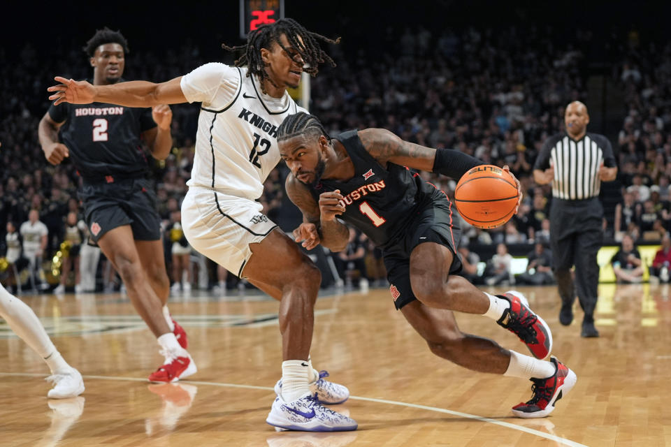 Houston guard Jamal Shead (1) drives around Central Florida guard DeMarr Langford Jr. (12) during the first half of an NCAA college basketball game, Wednesday, March 6, 2024, in Orlando, Fla. (AP Photo/John Raoux)