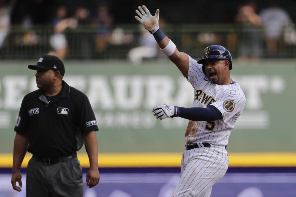 Milwaukee Brewers' Eduardo Escobar, right, reacts after hitting a two-RBI single during the second inning of a baseball game against the New York Mets, Sunday, Sept. 26, 2021, in Milwaukee. Escobar advanced to second base on a throwing error. (AP Photo/Aaron Gash)