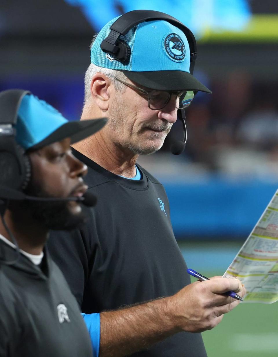 Carolina Panthers head coach Frank Reich (right) looks over an offensive play call sheet during action against the New Orleans Saints at Bank of America Stadium on September 18, 2023. as offensive coordinator Thomas Brown surveys the field. Reich announced on Oct. 16, 2023, that Brown would take over play-calling duties.