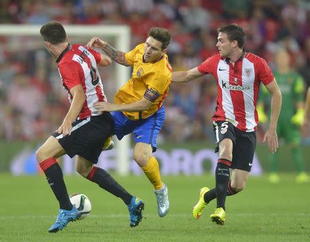 Barcelona's Lionel Messi (C) fights for the ball with Athletic Bilbao's Aymeric Laporte (L) and Javier Eraso during their Spanish Super Cup first leg soccer match at San Mames stadium in Bilbao, northern Spain, August 14, 2015. REUTERS/Vincent West