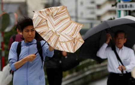 Passersby using umbrellas struggle against a heavy rain and wind wind caused by Typhoon Faxai in Tokyo