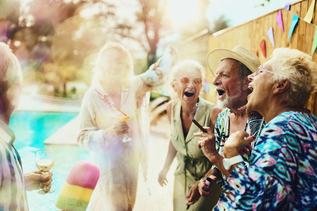 Group of carefree mature friends having fun while dancing and singing on a party during summer day by the pool. (skynesher / Getty Images)
