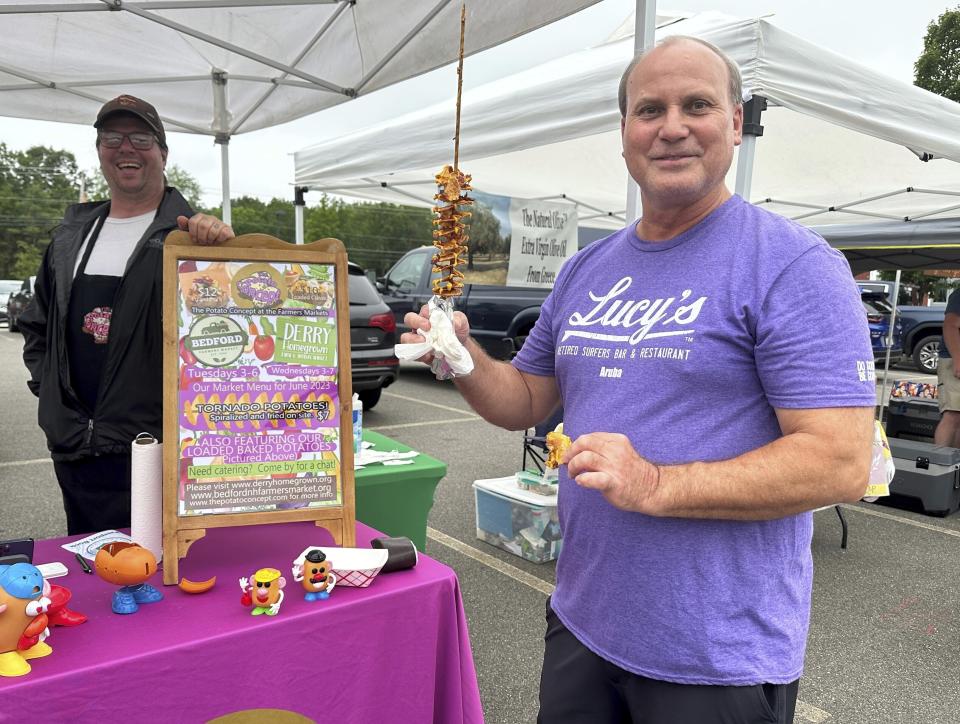 Tom Zapora, a Republican from Auburn, N.H., enjoys a fried potato on a stick at the Bedford Farmers Market on Tuesday, June 13, 2023. Zapora said he has been following the news about former President Trump's indictment closely, and is backing Florida Gov. Ron DeSantis in the 2024 GOP primary. (AP Photo/Holly Ramer)