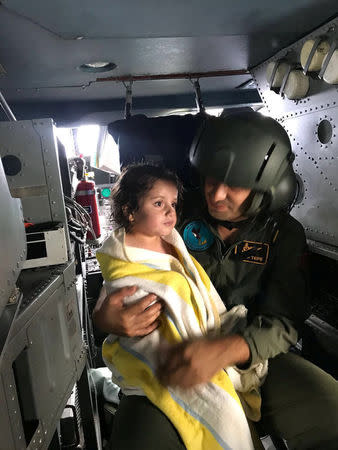 A Turkish military personnel holds a girl in a helicopter after she survied from a sunken migrant boat, in Kandira, Turkey, September 22, 2017. Turkish Military/Handout via REUTERS