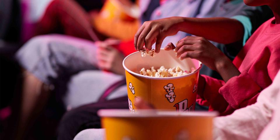 Midsection of friends sharing popcorn in a movie theater