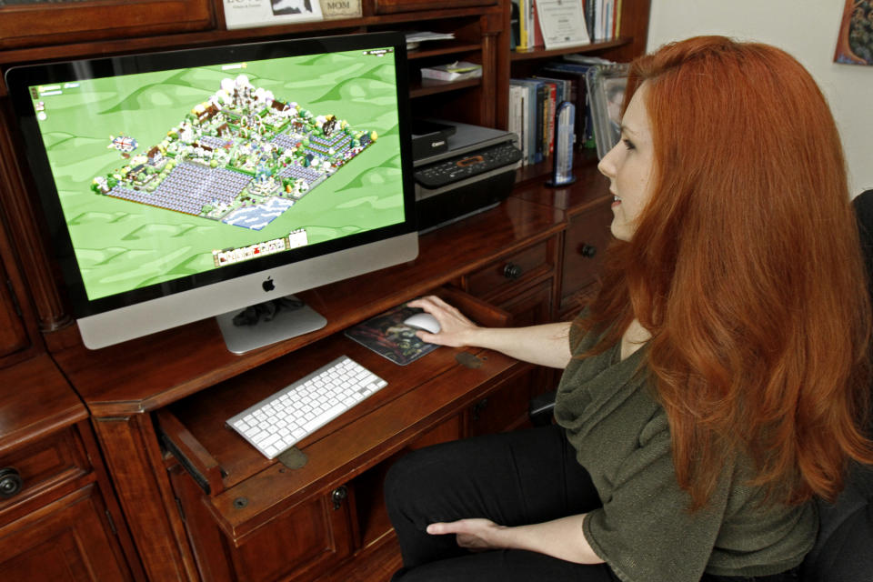 This Tuesday, April 26, 2011 photo shows Kyra Wilson playing Farmville on her computer at her home in New Haven, Vt. Wilson, a Vermont artist, is one of a small group that has mastered the agriculture planning game, Farmville. She just added a third virtual castle to her farm, which already has a French palace and a winery. She sells virtual wine to pay for the farm's expansion. (AP Photo/Toby Talbot)