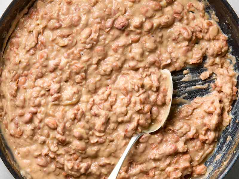 An overhead view of refried beans in a cast iron skillet.