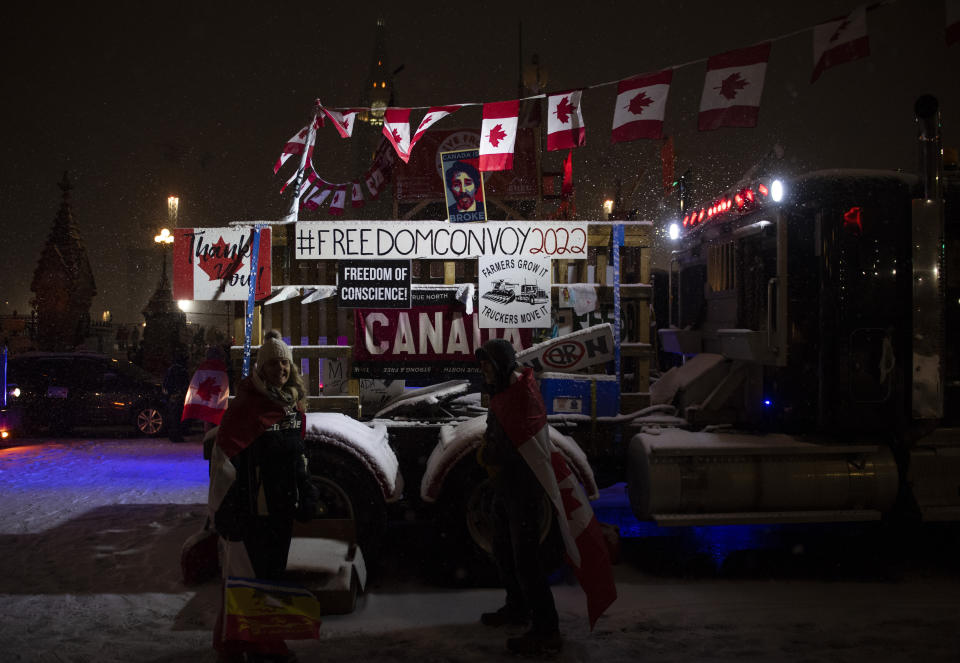 Snow falls as protesters stand by a semi-trailer truck on Wellington Street, on the 21st day of a protest against COVID-19 measures that has grown into a broader anti-government protest, on Thursday, Feb. 17, 2022, in Ottawa. (Justin Tang/The Canadian Press via AP)