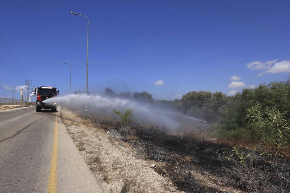 An Israeli firetruck extinguishes a fire on the Israeli side of the border between Israel and Gaza, near Kibbutz Zikim, Friday, Aug. 21, 2020. Palestinian militants fired 12 rockets at Israel from the Gaza Strip overnight, nine of which were intercepted, and Israel responded with three airstrikes on targets linked to the territory's militant Hamas rulers, the Israeli military said early Friday.(AP Photo/Tsafrir Abayov)