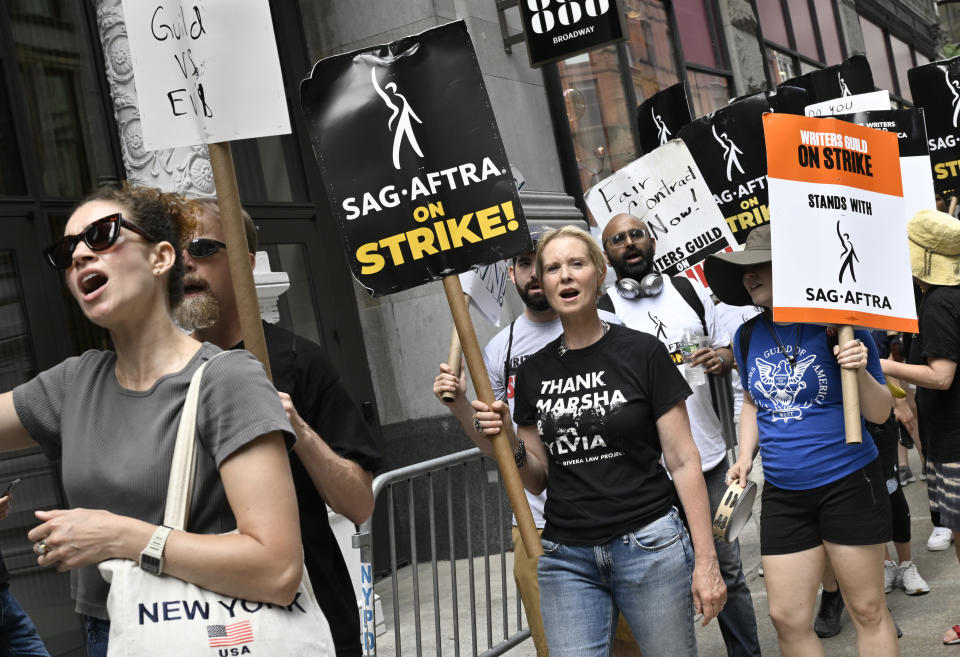Actor Cynthia Nixon, center, carries a sign on the picket line outside Netflix on Friday, July 21, 2023, in New York. The actors strike comes more than two months after screenwriters began striking in their bid to get better pay and working conditions. (Photo by Evan Agostini/Invision/AP)