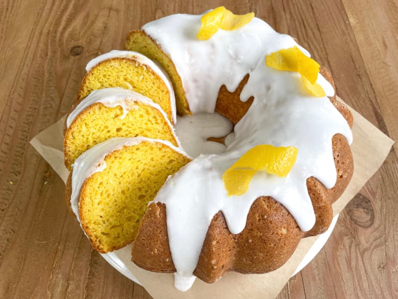 Whole lemon cake with slices ready to be plated.