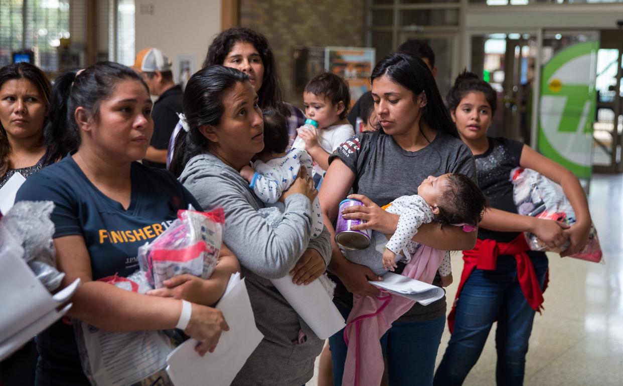 Immigrants wait to head to a nearby Catholic Charities relief center after being dropped off at a bus station shortly after release from detention through "catch and release" immigration policy on June 17 in McAllen, Texas. (Photo: Loren Elliott/Getty Images)