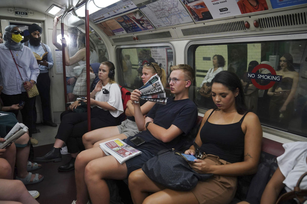 A man riding the Bakerloo line in central London uses a newspaper as a fan.