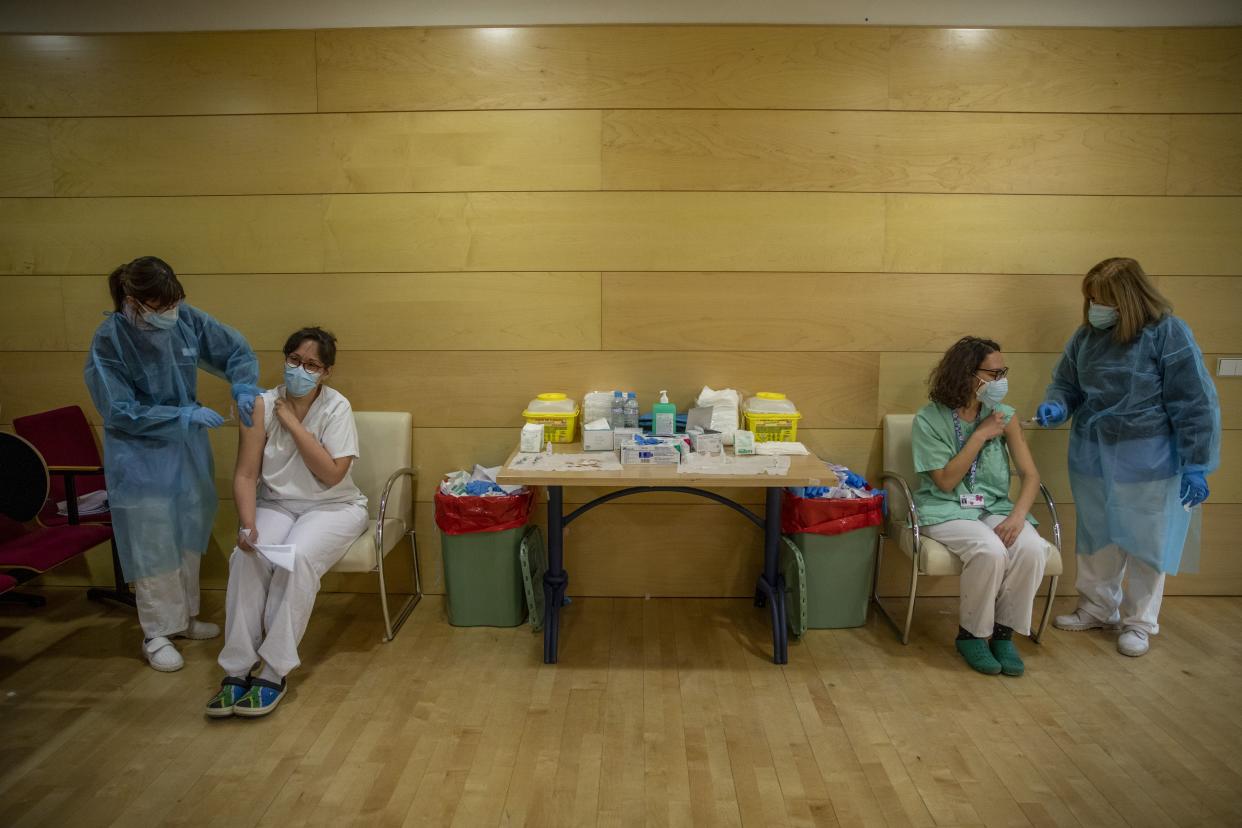 Health care workers receive a dose of the Pfizer-BioNTech COVID-19 vaccine at Gregorio Maranon Hospital during the third wave of the coronavirus pandemic on Jan. 14, 2021, in Madrid, Spain.