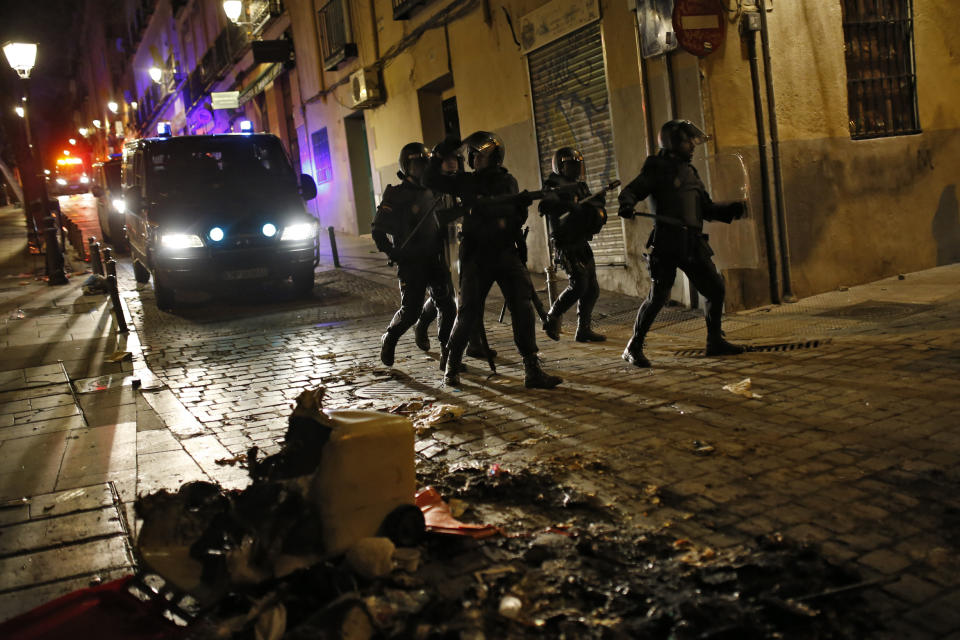 Los antidisturbios avanzan mientras que en el suelo se ve basura quemada (AP).