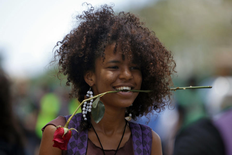 A student carries a flower in her mouth during a protest against a tuition increase outside the University of Puerto Rico in San Juan, Puerto Rico, Wednesday, April 23, 2014. The 24-hour protest was called even though officials at the university have extended a one year moratorium on the four percent increase. (AP Photo/Ricardo Arduengo)