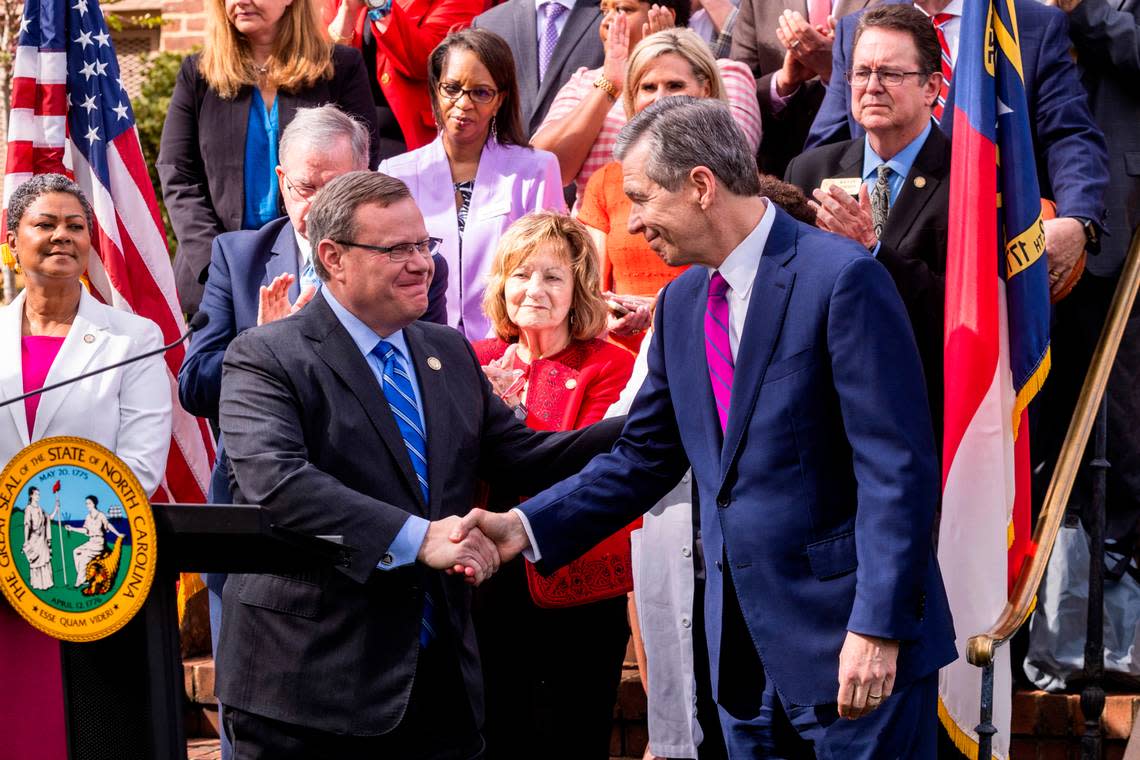 Gov. Roy Cooper, left, shakes hands with House Speaker Tim Moore before signing a Medicaid expansion bill into law during a ceremony at the Executive Mansion Monday, March 27, 2023.