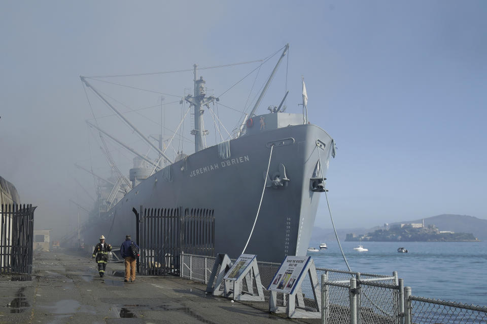 Fire officials stand in front of the SS Jeremiah O'Brien ship after a fire broke out before dawn at Fisherman's Wharf in San Francisco, Saturday, May 23, 2020. A warehouse was destroyed. Fire officials said no injuries have been reported Saturday morning and firefighters are making multiple searches to ensure no one was inside the building on Pier 45. (AP Photo/Jeff Chiu)