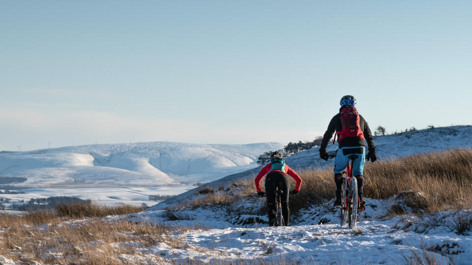  Two mountain bikers riding in the snow. 
