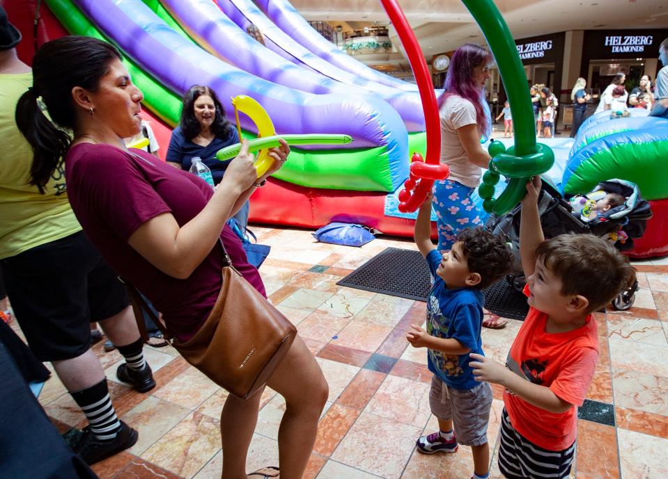 Julie Buxbaum, Wellington, defends herself with a bow and arrow made from balloons as she is under attack from her son, Aaron Buxbaum and Aaron Lovett, at The Mall at Wellington Green during a Hurricane Relief party.