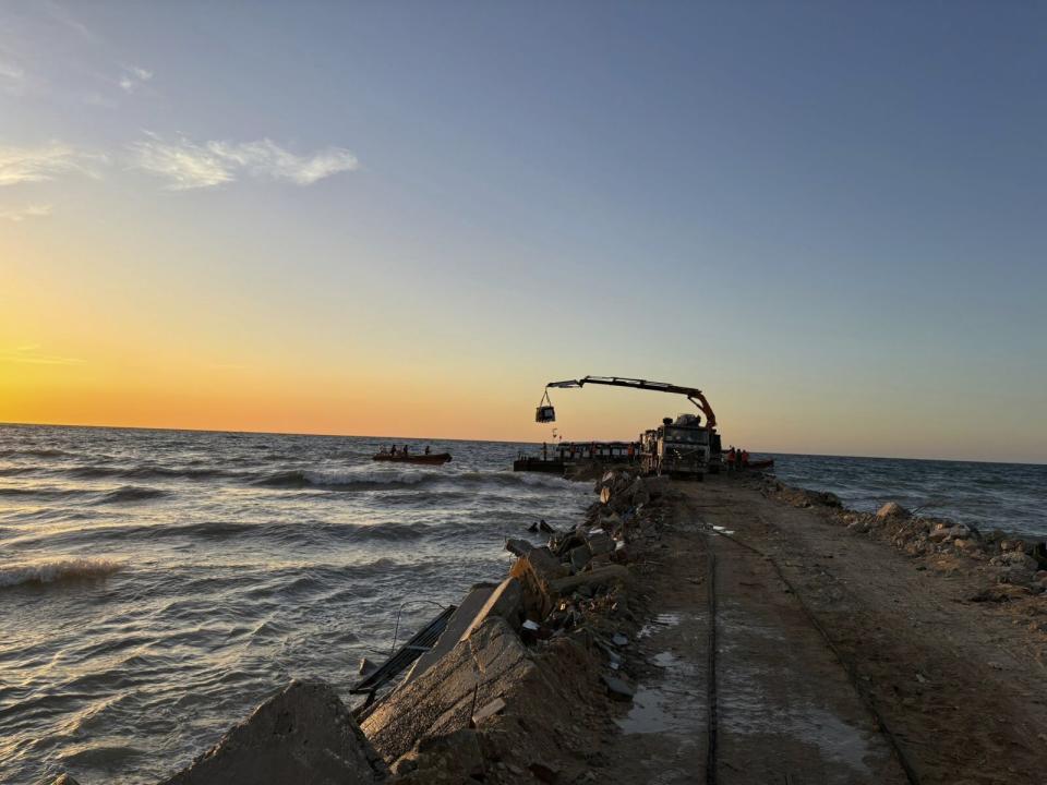 This photo provided by World Central Kitchen shows a crane unloading food packages over a makeshift port on the Gaza Strip, Saturday, March 16, 2024. Spanish NGO Open Arms has sent essential food to Gaza by a barge towed by a ship from Cyprus. The food was sent by World Central Kitchen, the charity founded by celebrity chef José Andrés, which operates kitchens providing free meals in Gaza. WCK said that it was offloading almost 200 tons of rice, flour and proteins on Saturday and that a second vessel is preparing to set sail from Cyprus with hundreds more tons of food. (World Central Kitchen via AP)