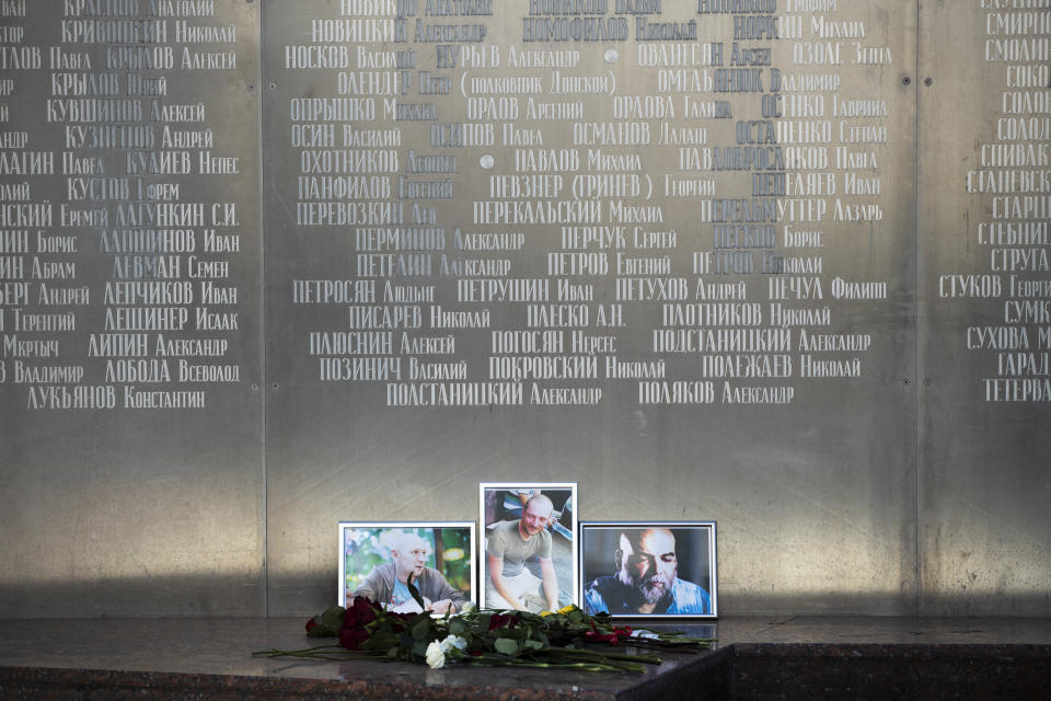 Flowers are placed by portraits of slain journalists Alexander Rastorguyev, Kirill Radchenko and Orkhan Dzhemal, at the Russian journalists Union building in Moscow, Russia, Wednesday, Aug. 1, 2018. Russian journalists who were killed in the Central African Republic had been working on an investigation into Russian private military contractors and the mining industries there, their editor said Wednesday. (AP Photo/Pavel Golovkin)