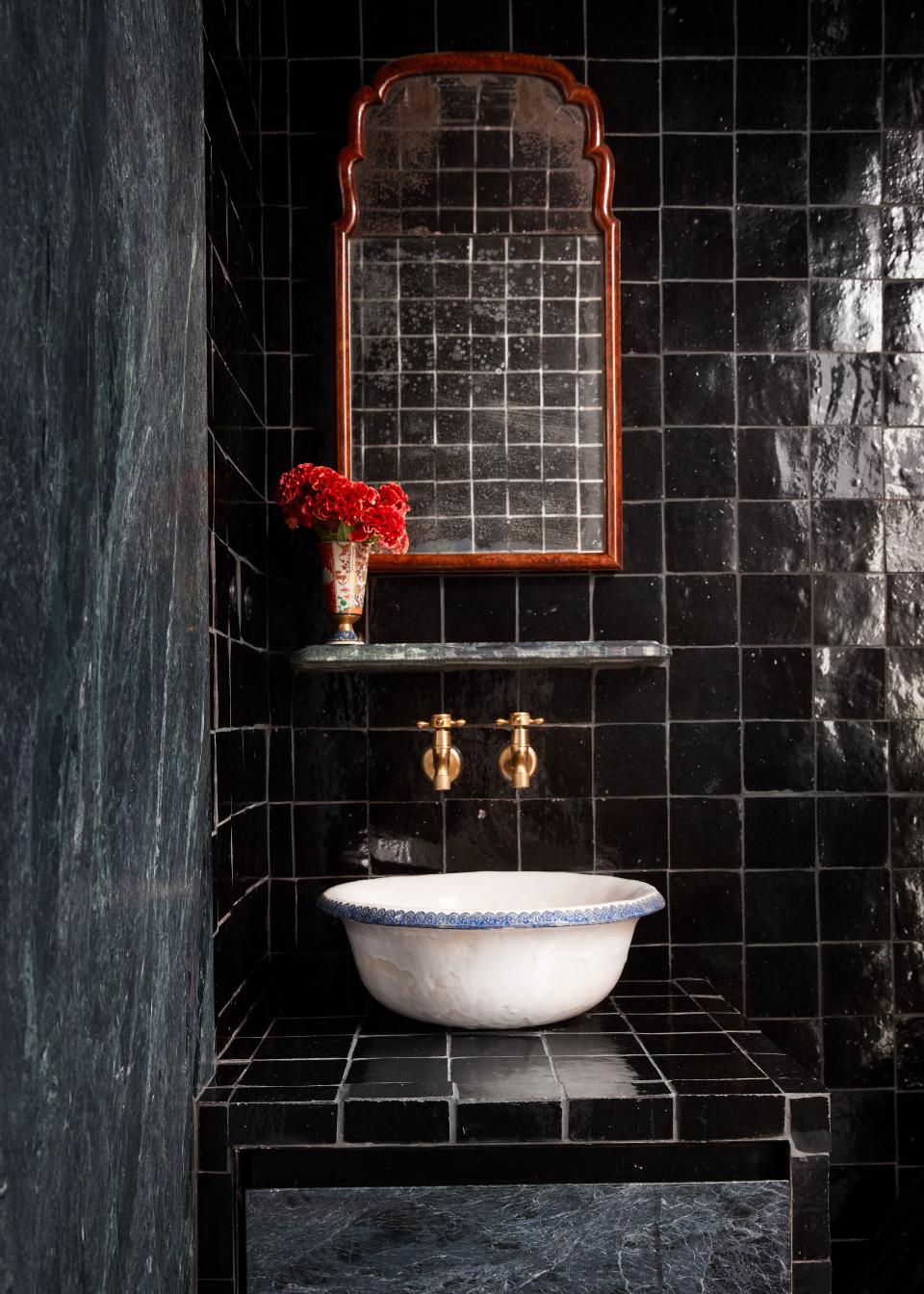 One of the bathrooms in the newly built apartment was renovated to look less “slick.” Valle chose handmade black tiles for the walls, and paired it with a small Moroccan sink. The red mirror above it is a vintage piece from Dienst and Dotter, and the stone below is Vermont Verde Antique serpentine.