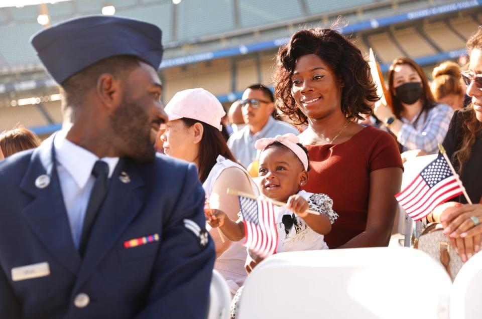 US Air Force Airman Michael Drah originally from Ghana, smiles with his wife and daughter before he becomes a US citizen at a naturalization ceremony at Dodger Stadium in Los Angeles, California (Getty)