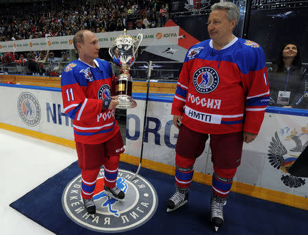 Russian President Vladimir Putin holds a trophy as Soviet former player Alexander Yakushev stands next to him after a gala game of the Night Ice Hockey League in Sochi, Russia, May 10, 2016. Mikhail Klimentyev/Sputnik/Kremlin via Reuters