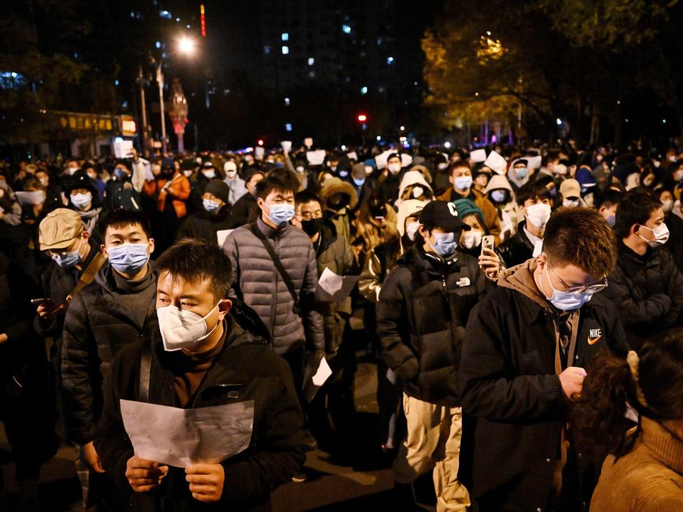 Protesters march along a street during a rally for the victims of a deadly fire as well as a protest against China's harsh Covid-19 restrictions in Beijing on November 28, 2022.