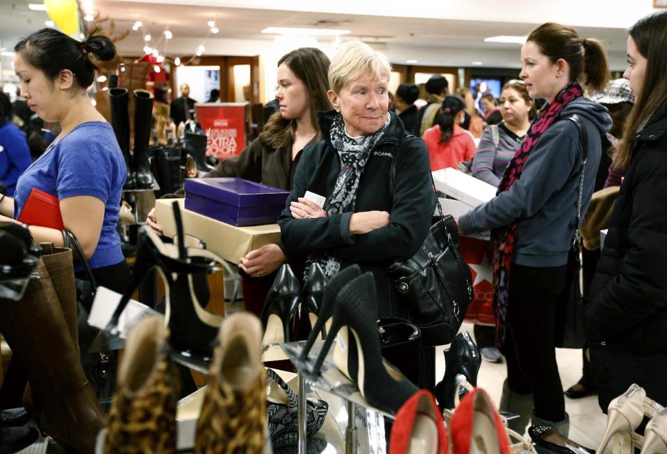 Cheryl Shedden, center right, of Beavercreek, Ohio, waits in the checkout line with her daughter Catie Smoot, center left, of Providence, R.I., at Macy's in downtown Boston, Friday, Nov. 23, 2012. Black Friday, the day when retailers traditionally turn a profit for the year, got a jump start this year as many stores opened just as families were finishing up Thanksgiving dinner. (AP Photo/Michael Dwyer)