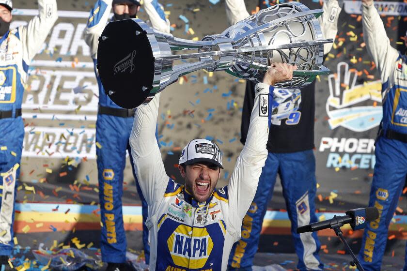 Chase Elliott holds up the season championship trophy as he celebrates with his race crew in Victory Lane after winning the NASCAR Cup Series auto race at Phoenix Raceway, Sunday, Nov. 8, 2020, in Avondale, Ariz. (AP Photo/Ralph Freso)