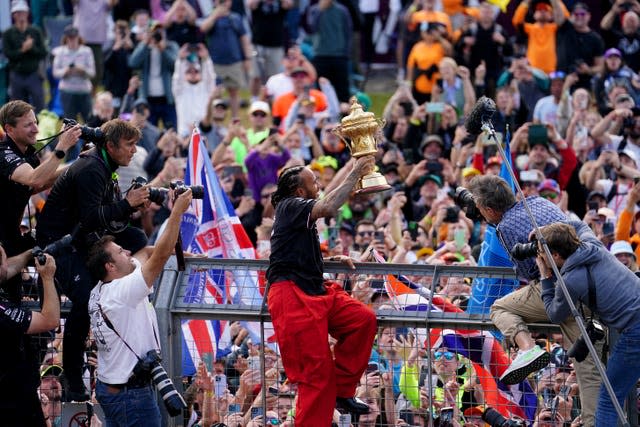 Mercedes’ Lewis Hamilton holds his trophy up to the fans