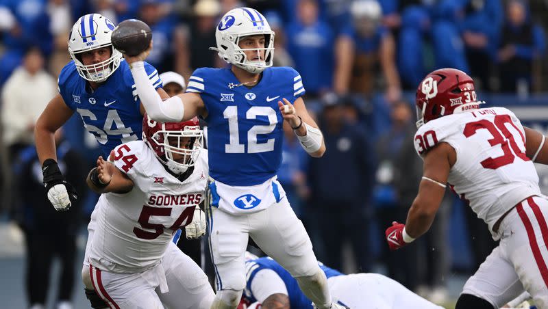 Brigham Young Cougars quarterback Jake Retzlaff (12) gets off the pass ahead of a hit by Oklahoma Sooners defensive linemen Jacob Lacey (54) and Trace Ford (30) as BYU and Oklahoma play at LaVell Edwards Stadium in Provo on Saturday, Nov. 18, 2023.