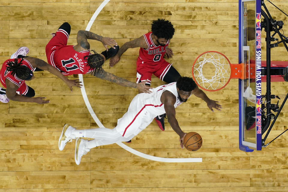 Philadelphia 76ers' Joel Embiid, bottom, tries to get a shot past Chicago Bulls' Coby White, from right, DeMar DeRozan and Ayo Dosunmu during the second half of an NBA basketball game, Monday, March 20, 2023, in Philadelphia. (AP Photo/Matt Slocum)