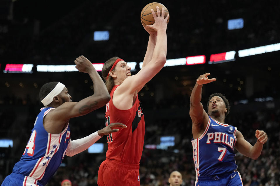 Toronto Raptors forward Kelly Olynyk (41) drives to the basket as Philadelphia 76ers forward Paul Reed (44) and guard Kyle Lowry (7) defend during the first half of an NBA basketball game Sunday, March 31, 2024, in Toronto. (Frank Gunn/The Canadian Press via AP)