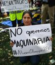 A woman whose relatives are feared buried in a building holds a sign saying "We don't want machinery" in a bid to stave off the use of bulldozers