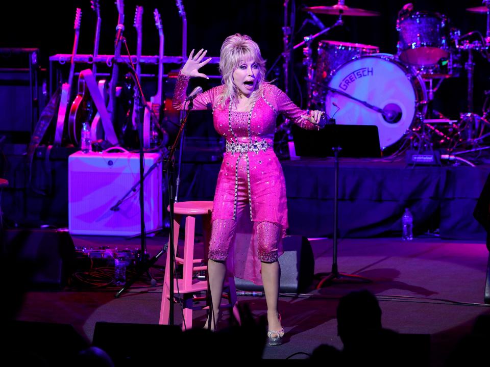 Dolly Parton on stage in a pink suit.