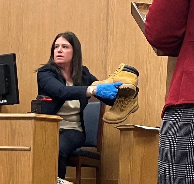 Devonie Herdeman, a DNA analyst with the Ohio Bureau of Criminal Investigation, shows the jury boots which included blood and DNA from both the defendant, David Perrine and the victim, Debra Perrine.