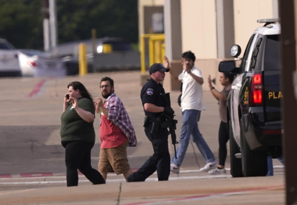 CORRECTS DATELINE TO ALLEN, TEXAS, INSTEAD OF FRISCO, TEXAS - People raise their hands as they leave a shopping center following reports of a shooting, Saturday, May 6, 2023, in Allen, Texas. (AP Photo/LM Otero)