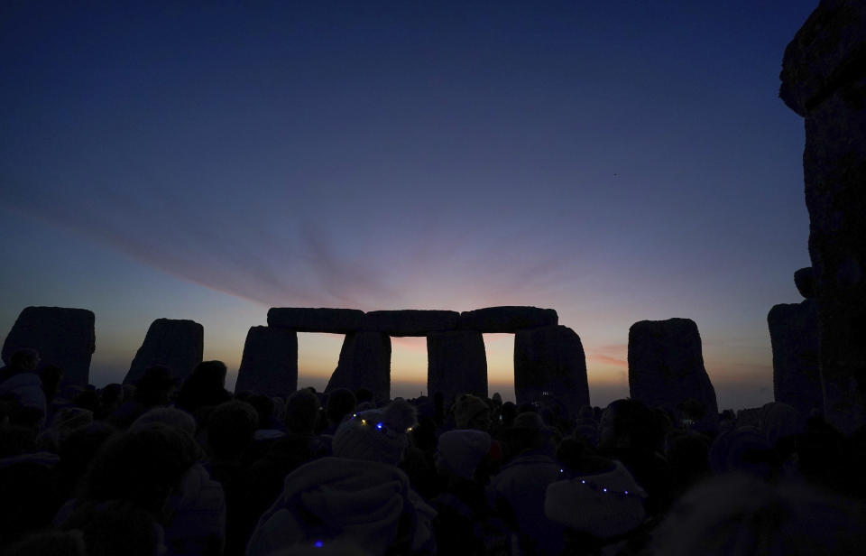 El amanecer comienza tras las piedras de Stonehenge durante las celebraciones del Solsticio de Verano en Wiltshire, Inglaterra, el martes 21 de junio de 2022. Tras dos años cerrado debido a la pandemia del COVID-19, Stonehenge reabrió el lunes para las celebraciones del Solsticio de Verano. (Andrew Matthews/PA via AP)