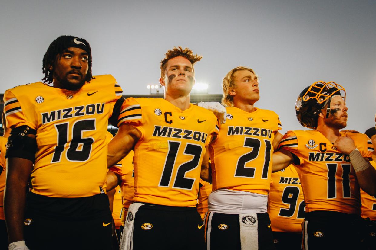 Missouri football players (from left to right) Johnny Walker Jr., Brady Cook, Sam Horn and Barrett Banister lock arms as Marching Mizzou plays "Old Missouri" on Oct. 22, 2022, at Faurot Field in Columbia, Mo. The Tigers defeated Vanderbilt 17-14.