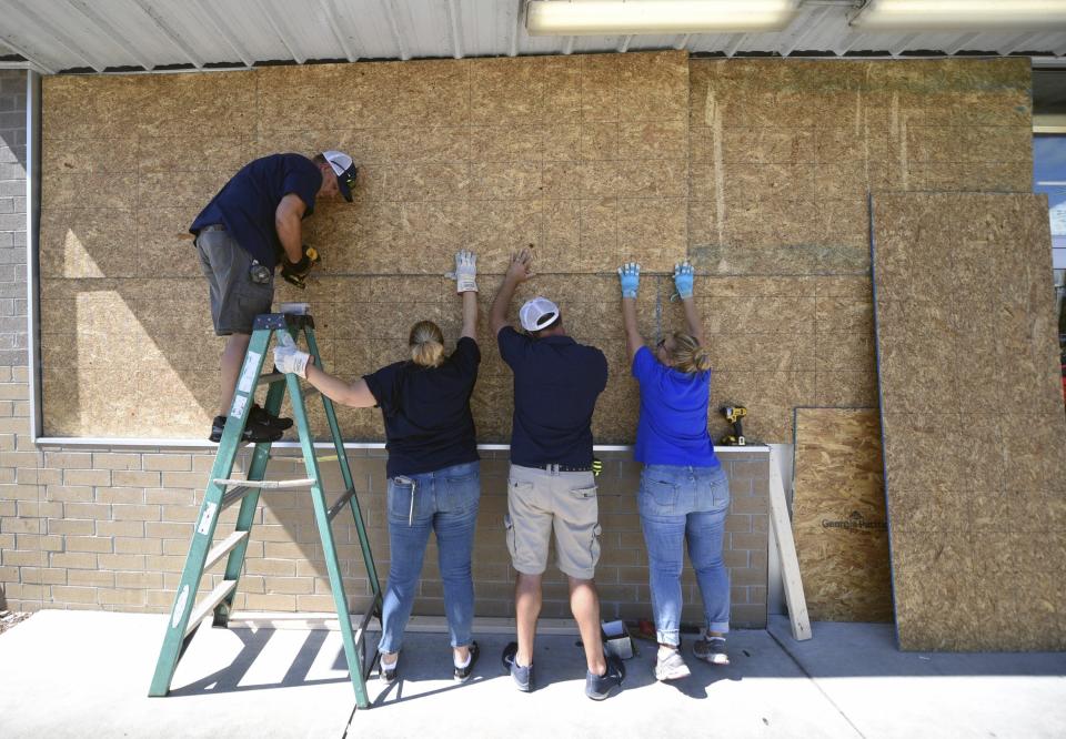 Jared Rogers, from left, Christine Bright, Stephen Bright and Marie Rogers board up a Family Dollar story in Wilmington, N.C., Tuesday, Sept. 3, 2019, as residents make preparations for Hurricane Dorian. (Matt Born/The Star-News via AP)