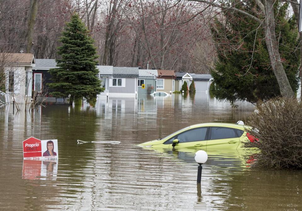 A car sits submerged in floodwater on Wednesday, May 1, 2019 in Ste-Marthe-sur-la-Lac, Que. A city northwest of Montreal has announced that its insurance company is suing the maker of a dike that burst during last year's spring floods, forcing the evacuation of thousands of residents.