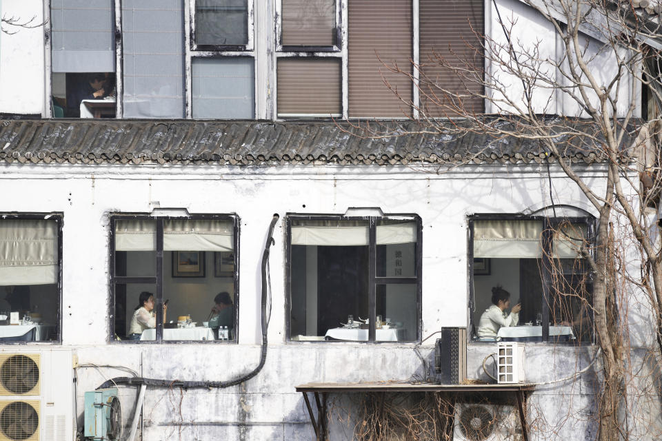 People enjoy their meals at a restaurant are seen through windows near the Forbidden City in Beijing, China, Saturday, March 16, 2024. (AP Photo/Tatan Syuflana)